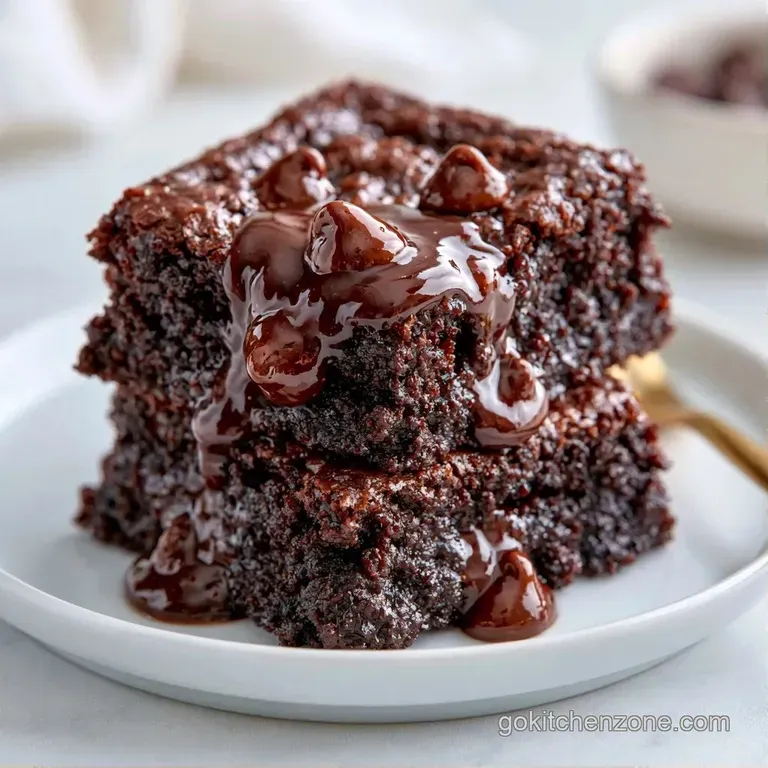 A moist dark chocolate square dusted with powdered sugar on a white porcelain plate beside a fresh raspberry.