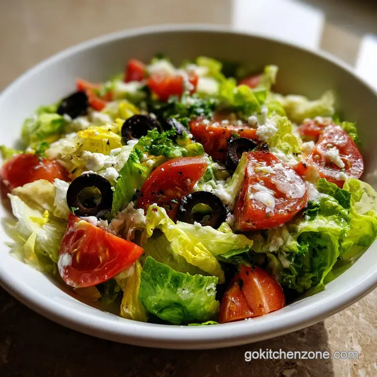 A plated Olive Garden salad: glistening lettuce, bright orange tomatoes, black olives, with a creamy dressing on the side.